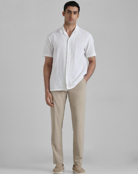 Man wearing white short sleeve casual shirt with beige trousers in minimal studio setting