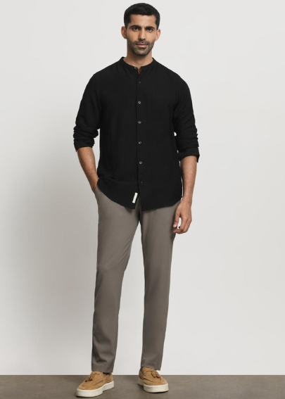 Man wearing black casual shirt with grey trousers and sneakers in studio background