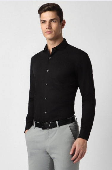 Man wearing black formal shirt with grey trousers in modern studio setting