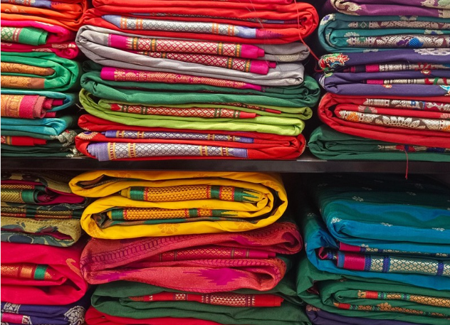 Stack of colorful traditional sarees neatly folded on shelves
