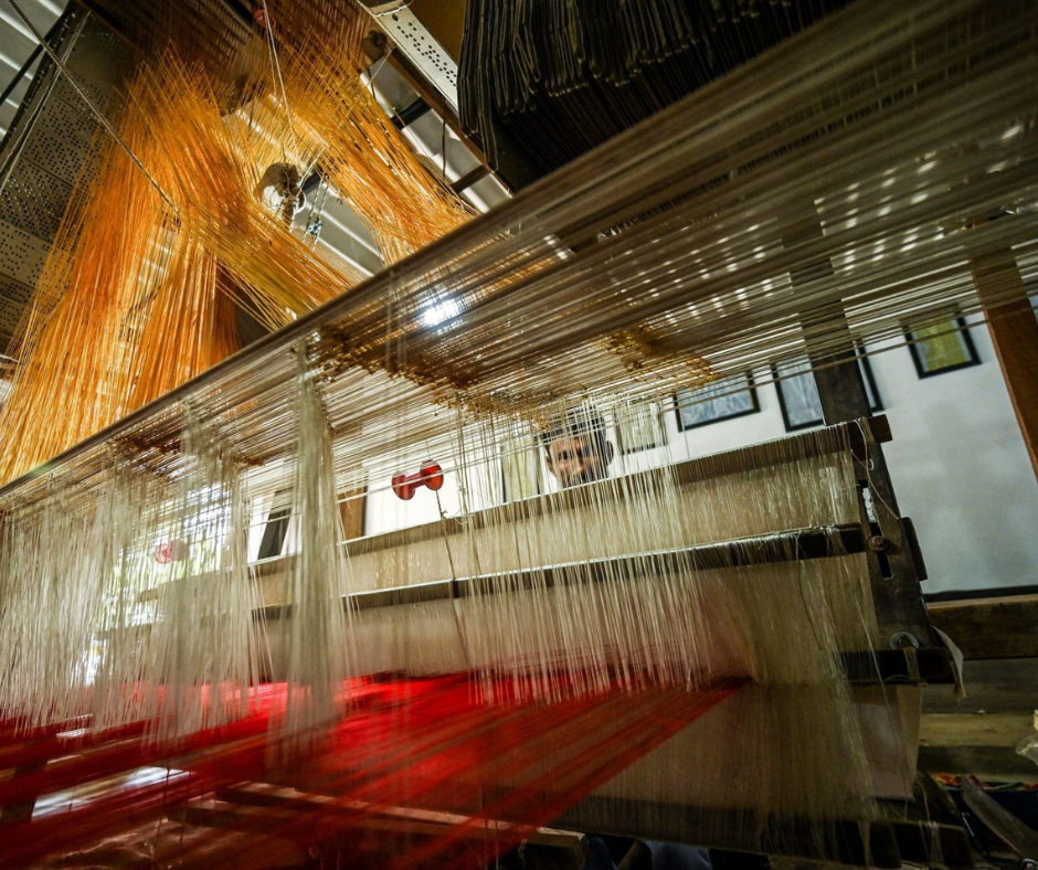 Traditional handloom weaving process with threads being used to create fabric